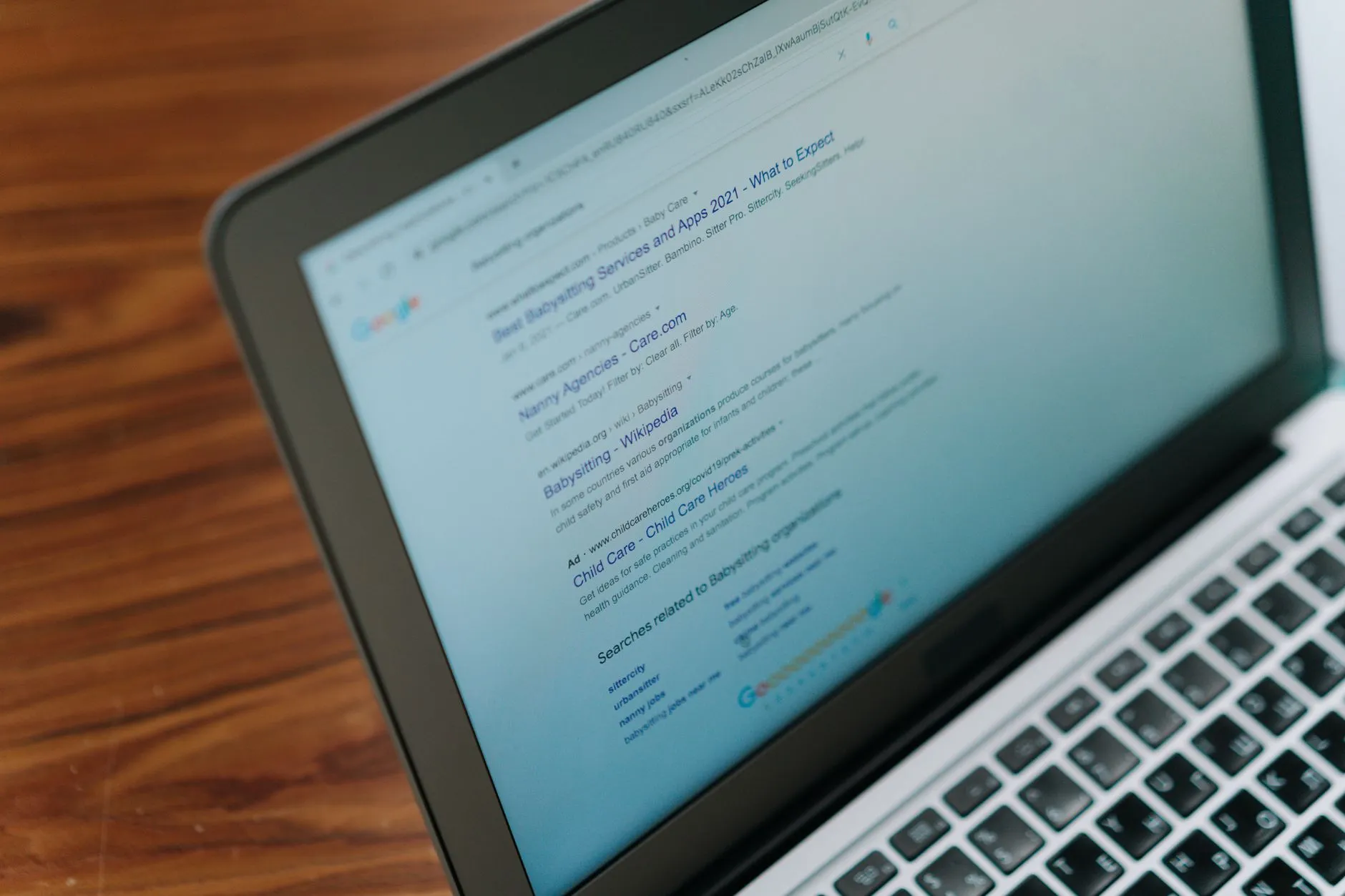 A laptop on a wooden desk showing a page of classic Google search results