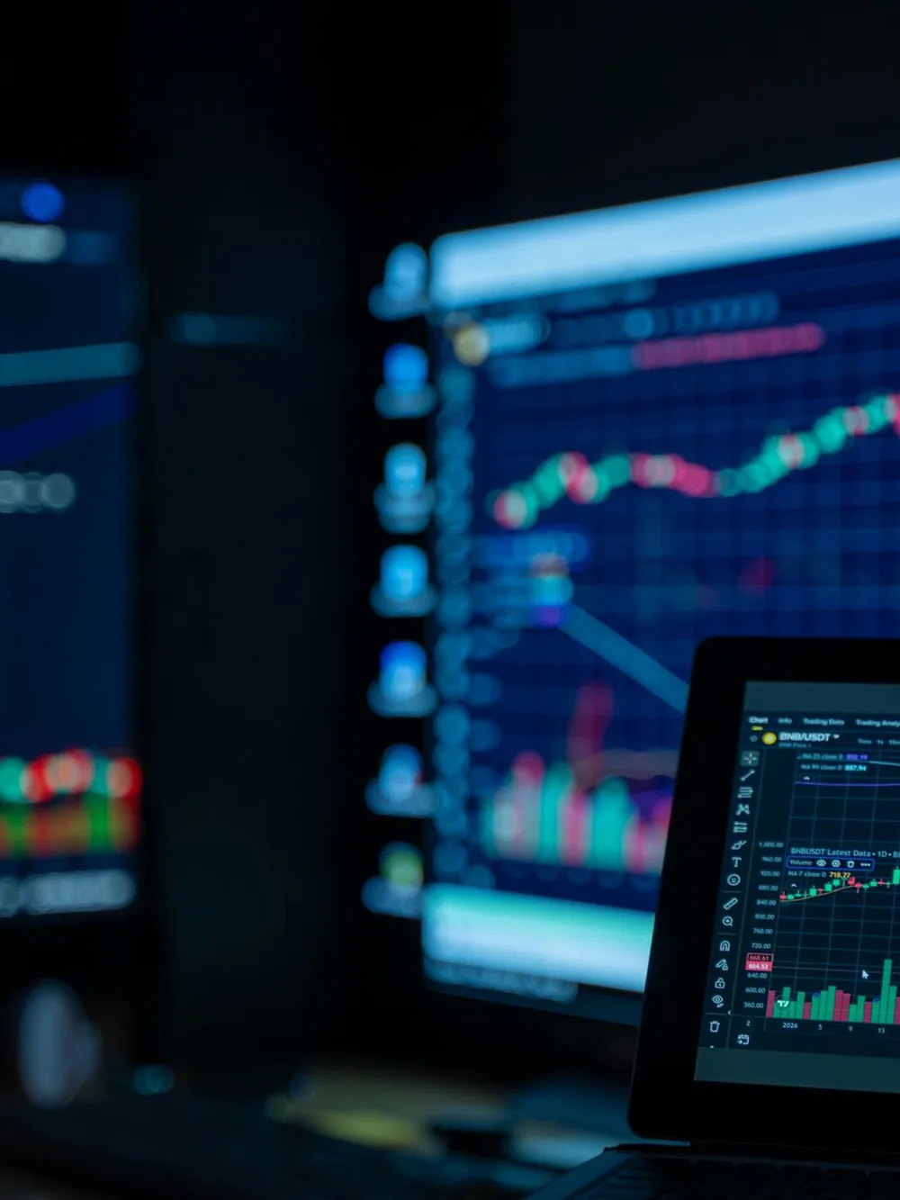 Monitors showing market charts in a dimly lit room